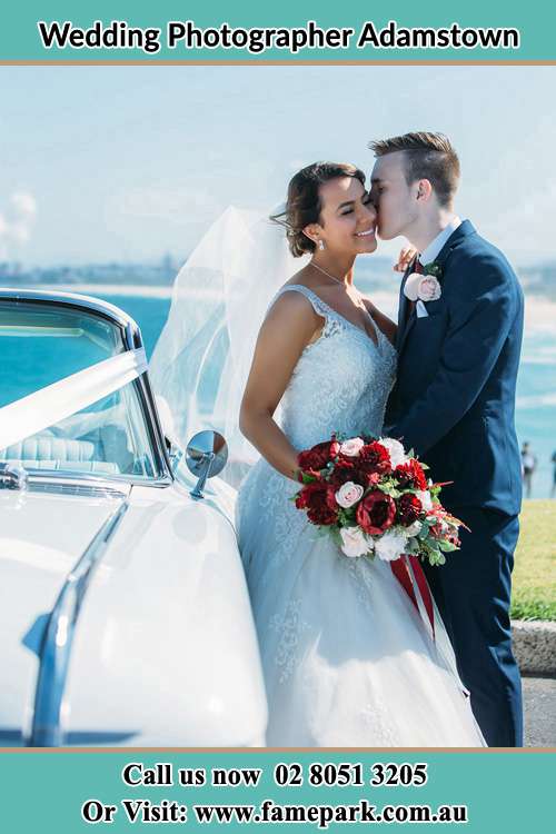 The Groom kissing his Bride besides their bridal car Adamstown