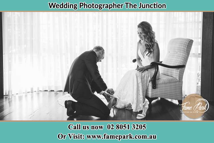 The Bride is being helped by the Groom trying to put on her shoes The Junction