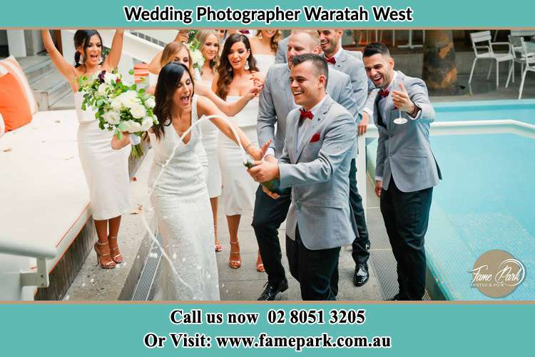 Photo of the Groom open a champagne for celebration with his Bride, the groom men and bridesmaids